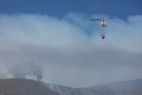Helicopter flies with an extinguishing water tank to a fire