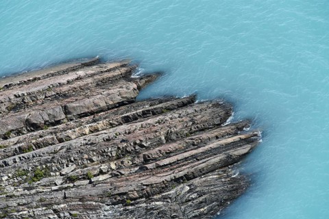 Glacial smooth-cut rock juts out into turquoise-blue Lake Argentino