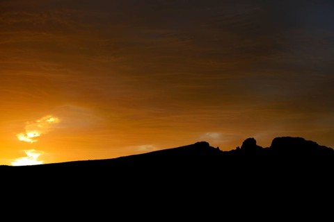 Dramatic sunset with rising storm clouds in front of mountain silhouette