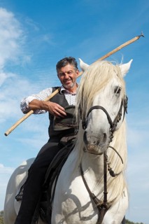 Gardian or traditional bull herder in typical working clothes on a Camargue horse