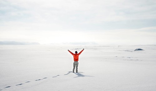 Young man stands alone in snowy landscape