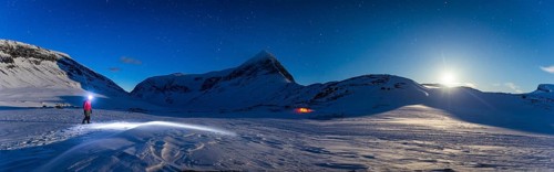 Person with tent on full moon in the snow
