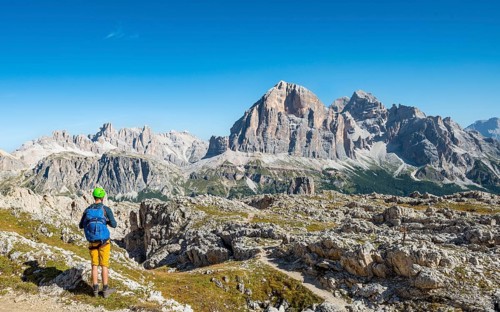 Hiker with climbing helmet on footpath to the Nuvolau