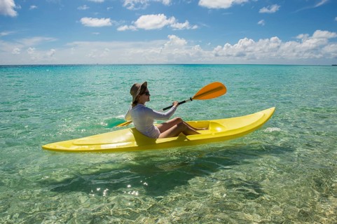 Female tourist kayaking in the turquoise waters of Tikehau