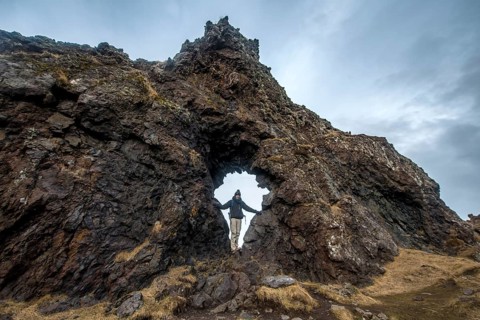 Young man stands in rock arch