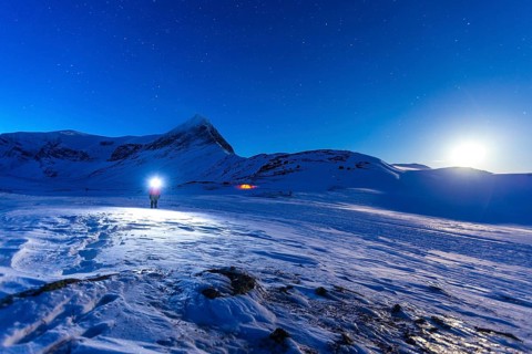 Person with tent on full moon in the snow