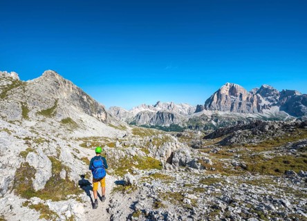 Hiker with climbing helmet on footpath to the Nuvolau
