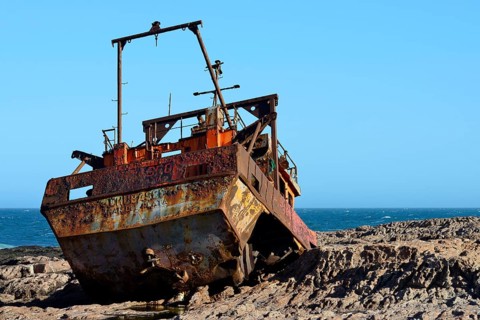 Rusty wreck of a fish trawler on the rocky shore