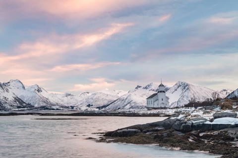 Church of Gimsoy surrounded by snowy mountains and coast