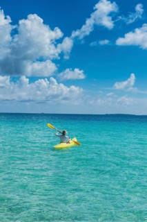 Female tourist kayaking in the turquoise waters of Tikehau
