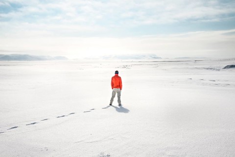 Young man stands alone in snowy landscape