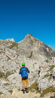 Hiker with climbing helmet on footpath to Nuvolau