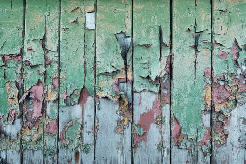 Peeling green and red paint on wooden wall