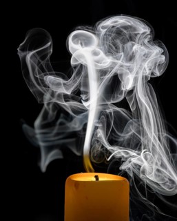 Smoky candle in front of a black background