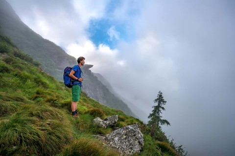 Hiker climbing the Greifenberg with wafts of mist