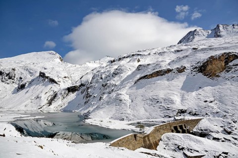 Nassfeld reservoir with dam at 2233 m on the Grossglockner High Alpine Road with snowy mountains
