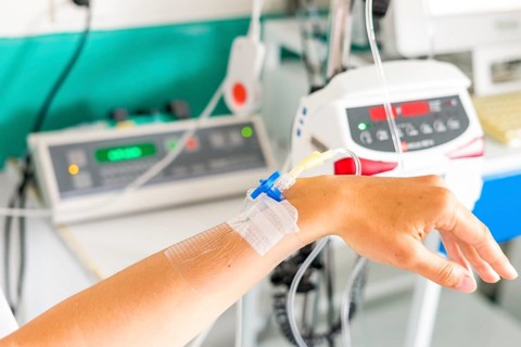 Hand with peripheral venous catheter and equipment to dose epidural during delivery