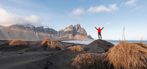 Man in red jacket stretches arms into the air