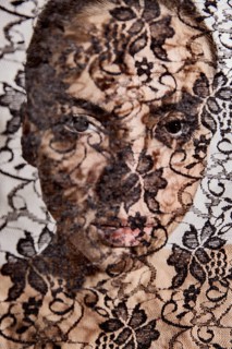 Face of a beautiful woman behind a transparent cloth with floral pattern