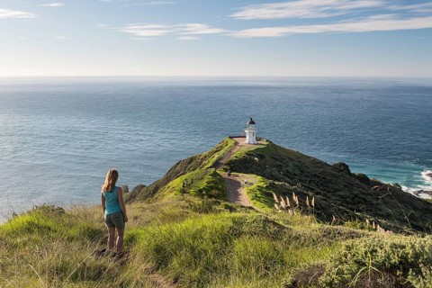 Woman stands in front of lighthouse at Cape Reinga