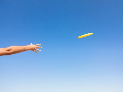 Man throwing a frisbee against blue sky