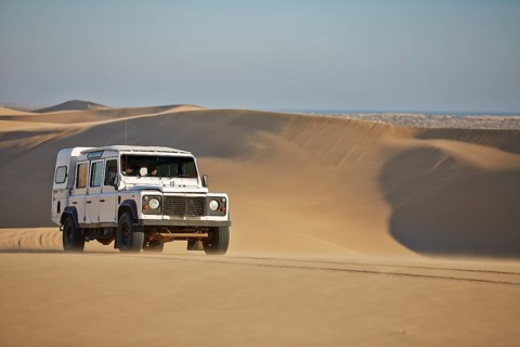 Off-road vehicle drives over sand dunes at Lange Wand on the Atlantic coast