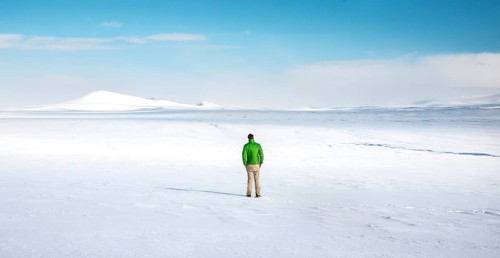 Young man stands alone in snowy landscape