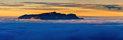 From the clouds towering mountain massif Hochthron at sunset