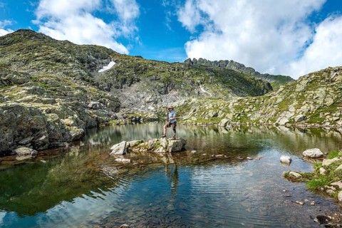 Hiker on a stone in a small lake