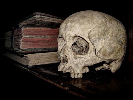 Skull and old books on bookshelf