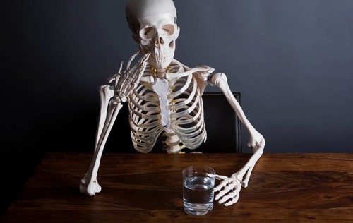 Skelett sits at the table with a glass of water in his hand