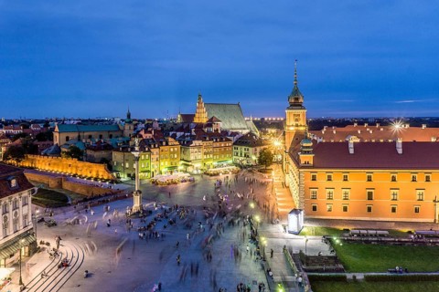 Royal Castle and Sigmund Column monument with many people passing by in the evening