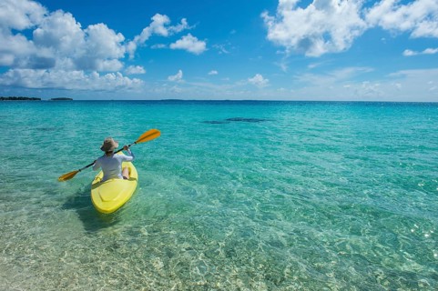 Female tourist kayaking in the turquoise waters of Tikehau