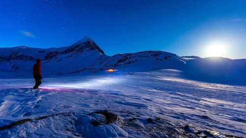 Person with tent on full moon in the snow