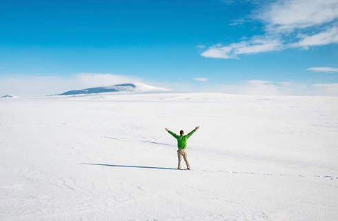 Young man stands alone in snowy landscape