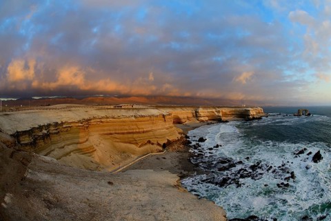 Rocky coast with arch La Portada at sunset with clouds