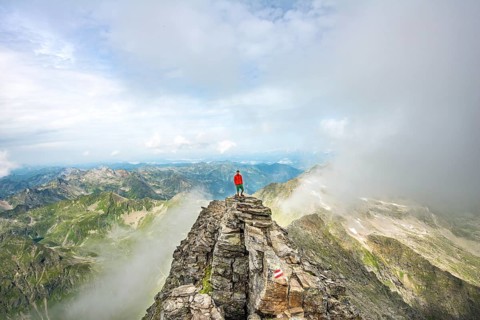 Hiker on the summit of the Hochgolling with rising fog
