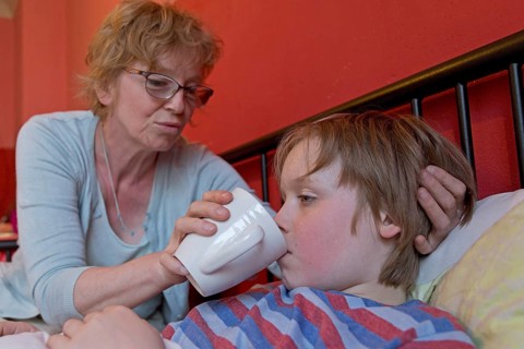 Mother takes care of sick son in bed