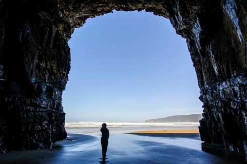 Woman standing in the giant entrance of Cathedral caves in backlit