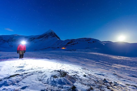 Person with tent on full moon in the snow