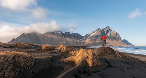 Man in red jacket stretches arms into the air