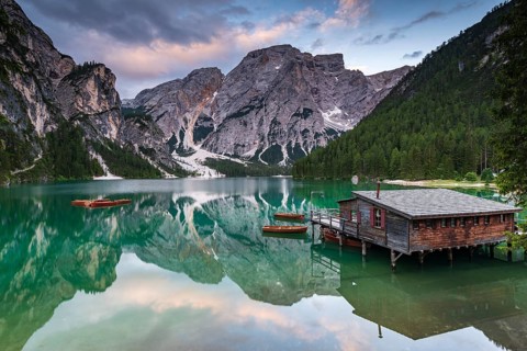 Green mountain lake with boats and boathouse