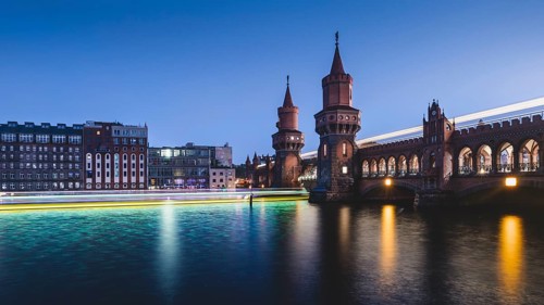 Berlin Oberbaum Bridge with traces of light from ship and train in the evening