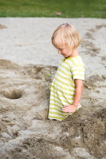 Toddler with 3 years on a playground in the sandbox
