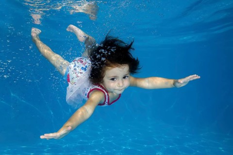Little girl learns to swim underwater in the pool