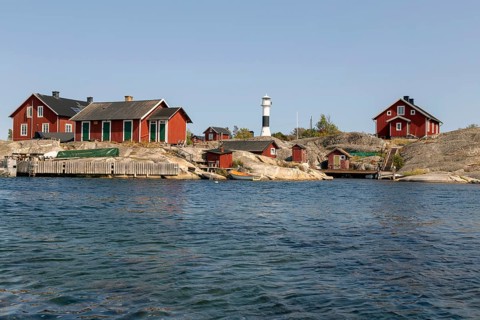 Red wooden houses with lighthouse on the rocky coast