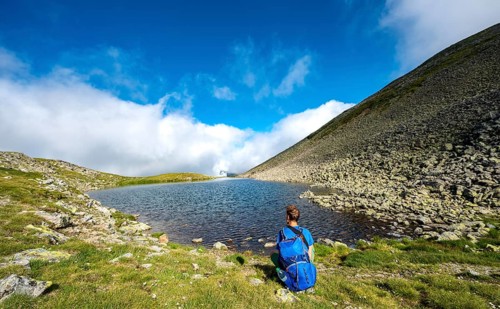 Hiker at the Sattelsee lake at the Greifenbergsattel
