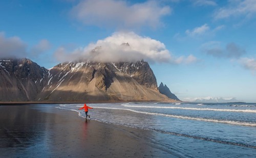 Man runs in a good mood on a black sandy beach