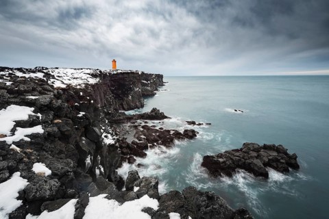 Orange lighthouse Ondverdarnes stands on a dark cliff