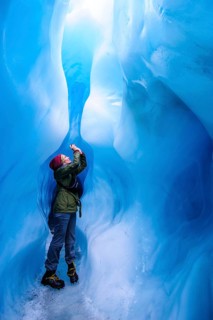 Woman photographing in a ice cave in Fox Glacier